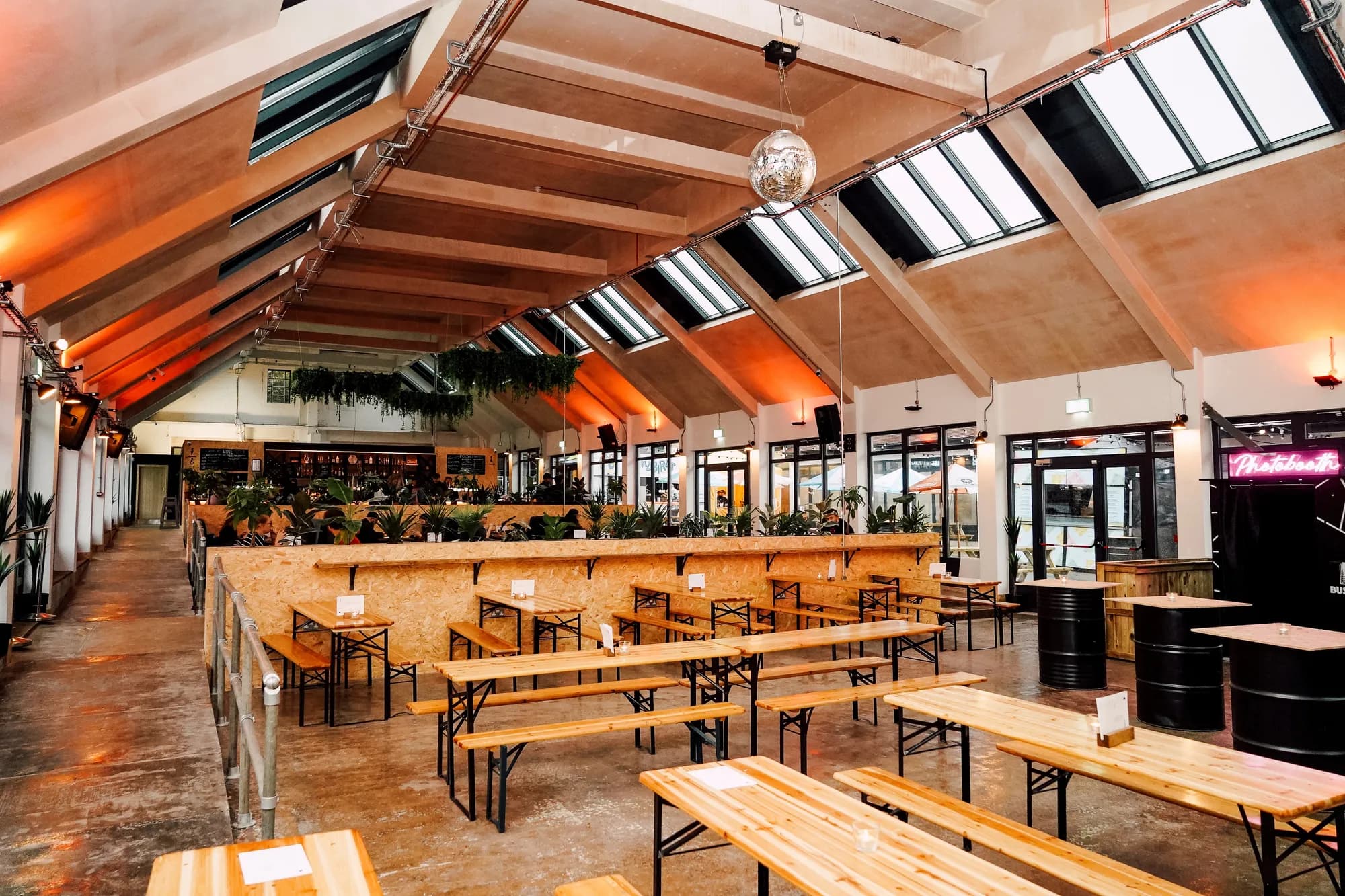 Inside Bustler: long wooden benches under a skylit roof, the bar at the back